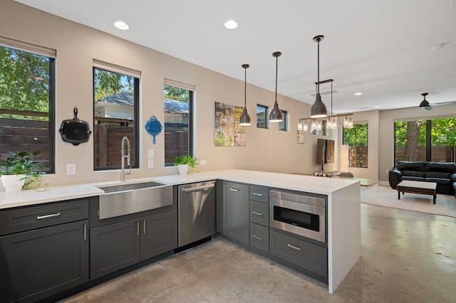 kitchen featuring built in microwave, sink, hanging light fixtures, stainless steel dishwasher, and kitchen peninsula