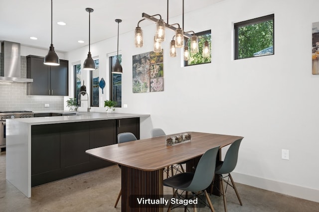 kitchen with high end stove, backsplash, a kitchen breakfast bar, and wall chimney exhaust hood