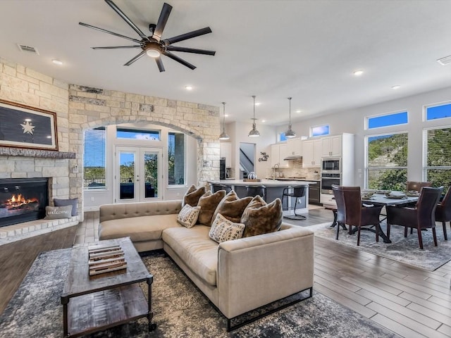 living room featuring a fireplace, ceiling fan, a wealth of natural light, and dark hardwood / wood-style flooring