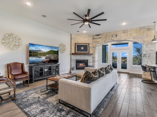 living room with french doors, a fireplace, and ceiling fan