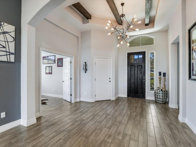 entryway with a towering ceiling, a notable chandelier, and beam ceiling