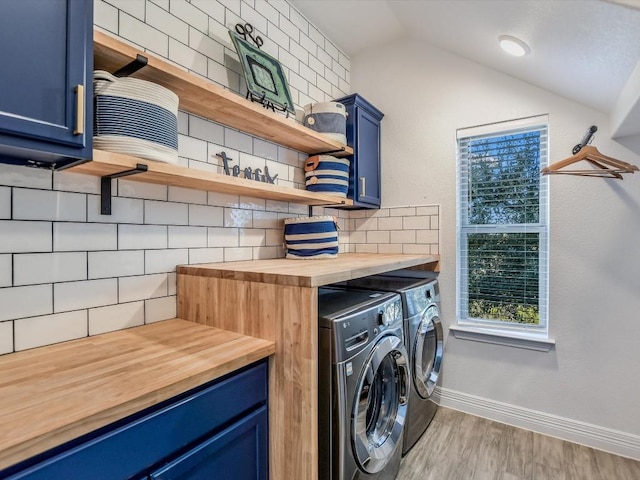 washroom featuring washing machine and dryer, cabinets, and light hardwood / wood-style floors