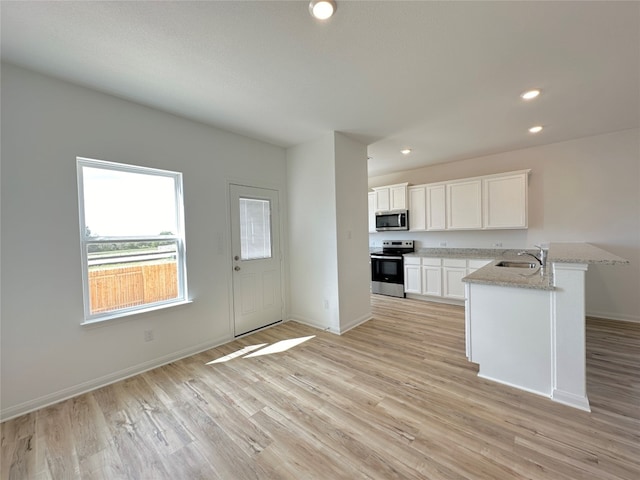 kitchen with light stone countertops, sink, stainless steel appliances, light hardwood / wood-style flooring, and white cabinets