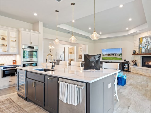 kitchen featuring white cabinets, stainless steel double oven, sink, and a tray ceiling