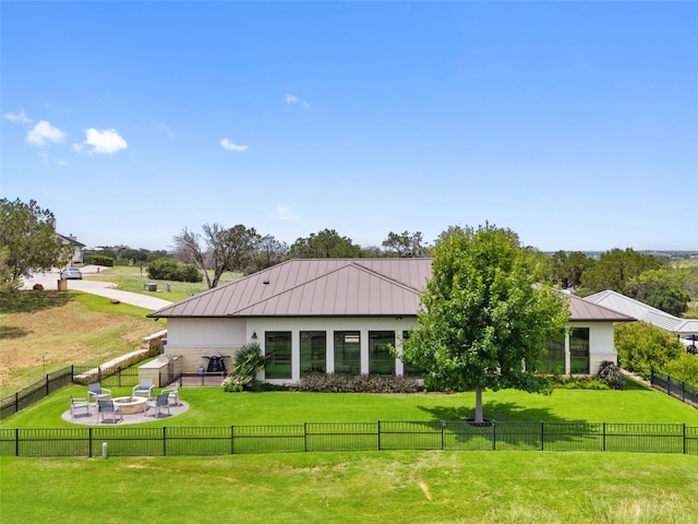 back of property with a fire pit, a patio area, and a lawn