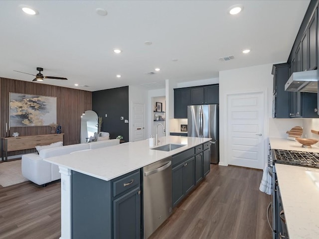 kitchen featuring ceiling fan, sink, dark wood-type flooring, an island with sink, and appliances with stainless steel finishes