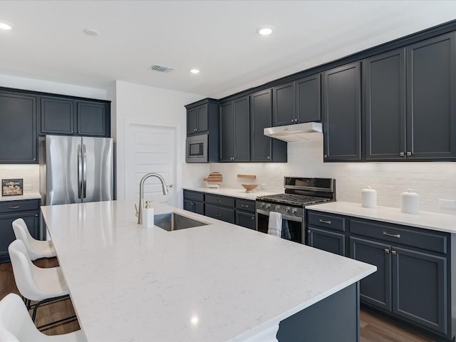 kitchen with a breakfast bar, sink, an island with sink, and appliances with stainless steel finishes