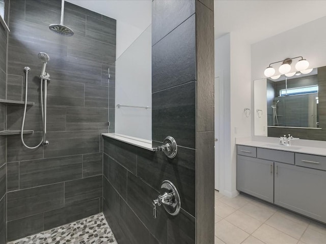 bathroom with tile patterned flooring, a tile shower, and vanity