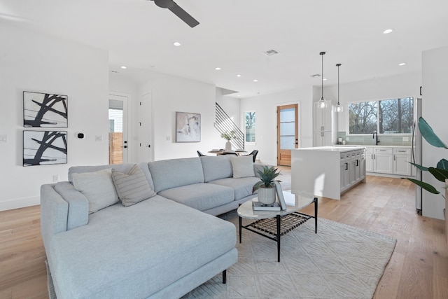 living room featuring ceiling fan, plenty of natural light, light hardwood / wood-style floors, and sink