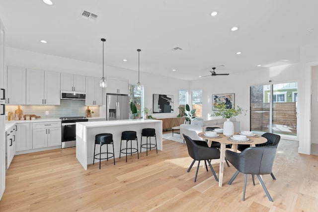 kitchen with ceiling fan, appliances with stainless steel finishes, a kitchen island, white cabinetry, and extractor fan