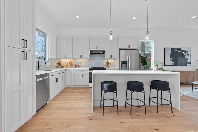 kitchen featuring pendant lighting, white cabinets, sink, a kitchen island, and stainless steel appliances