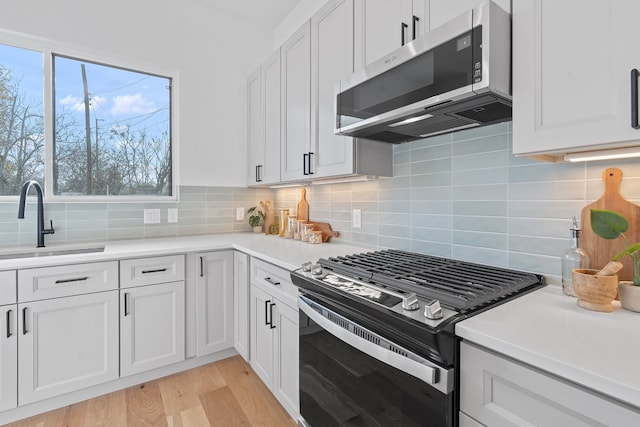 kitchen featuring white cabinets, sink, stainless steel appliances, and tasteful backsplash