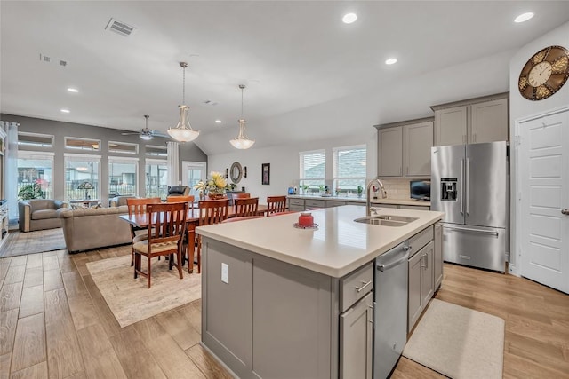 kitchen with gray cabinetry, sink, ceiling fan, an island with sink, and appliances with stainless steel finishes