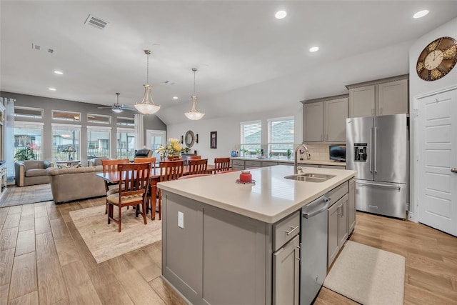 kitchen featuring stainless steel appliances, a sink, gray cabinets, and light wood-type flooring