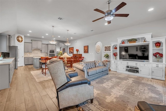 living room with ceiling fan, sink, and light wood-type flooring