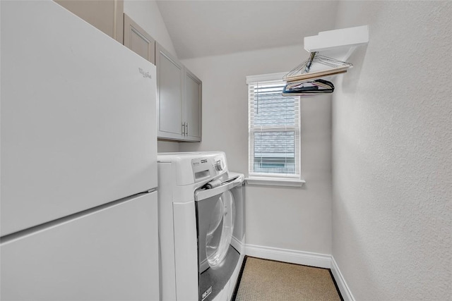 clothes washing area featuring cabinets and independent washer and dryer