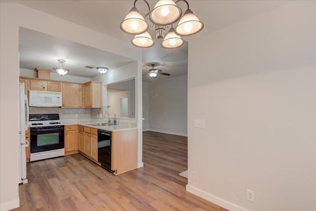 kitchen with backsplash, ceiling fan with notable chandelier, white appliances, sink, and light brown cabinets