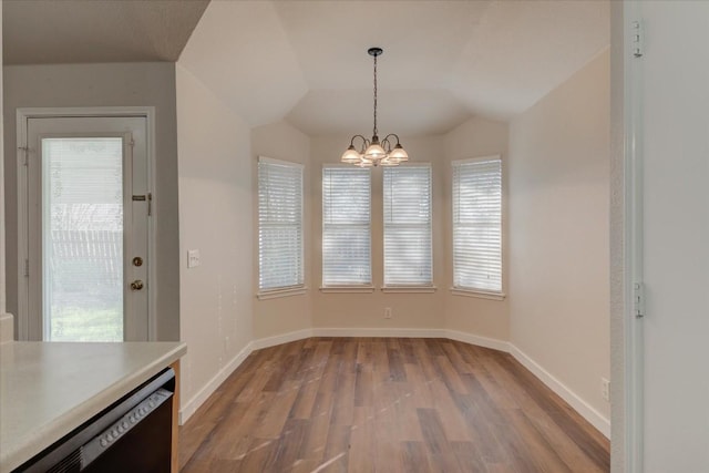 unfurnished dining area featuring a chandelier, wood-type flooring, and vaulted ceiling