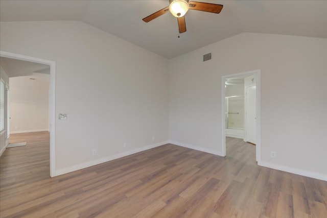 empty room featuring ceiling fan, vaulted ceiling, and light wood-type flooring