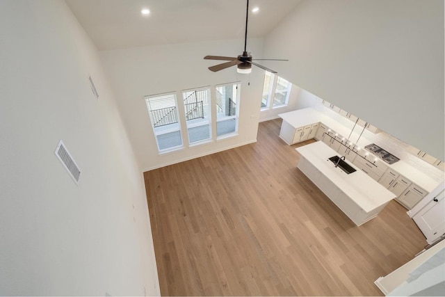 unfurnished living room featuring ceiling fan, visible vents, high vaulted ceiling, light wood-style floors, and recessed lighting