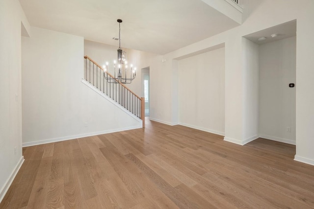 interior space featuring an inviting chandelier, baseboards, stairs, and wood finished floors