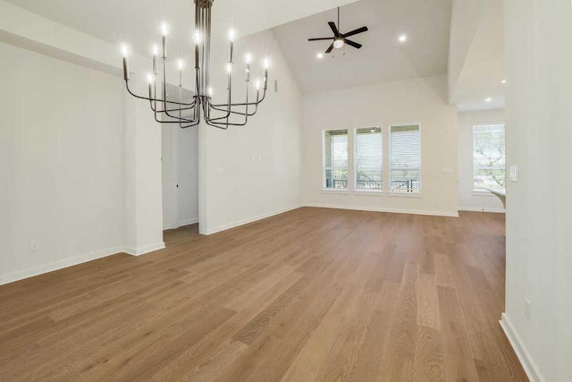 unfurnished dining area featuring baseboards, plenty of natural light, wood finished floors, and ceiling fan with notable chandelier