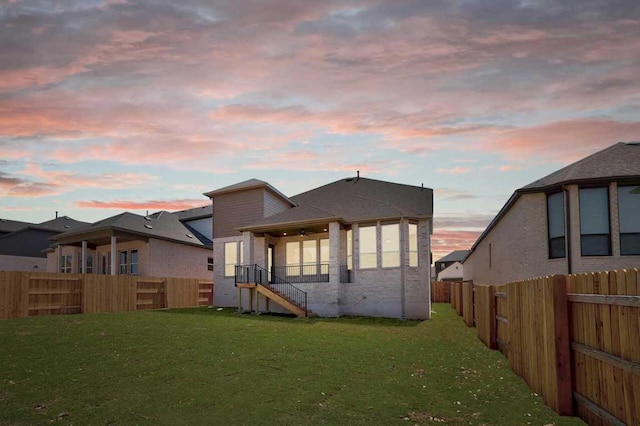 rear view of house featuring a fenced backyard and a yard