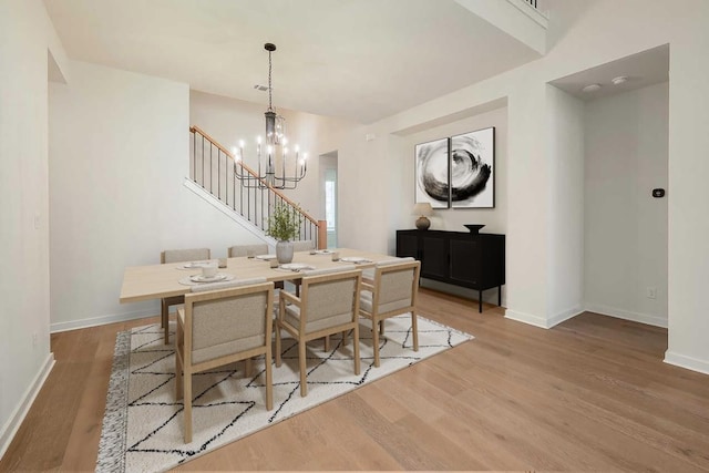 dining area featuring baseboards, a notable chandelier, wood finished floors, and stairway