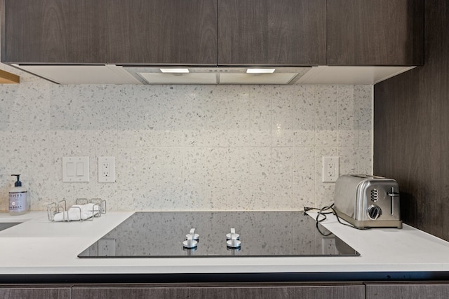 interior space featuring dark brown cabinets, backsplash, and black electric cooktop