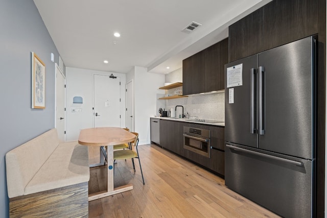 48 E Ave Unit 1607, Austin, TX 78701 - kitchen with stainless steel appliances, open shelves, a sink, dark brown cabinets, and light wood finished floors