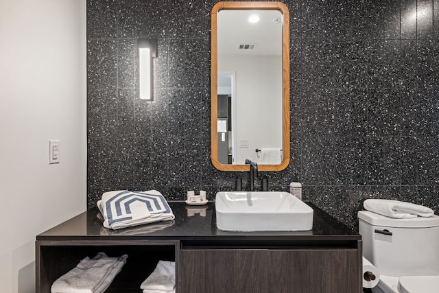 bathroom with decorative backsplash, vanity, tile walls, and toilet