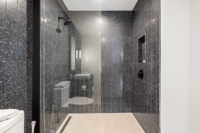 bathroom with a tile shower, tile walls, and toilet