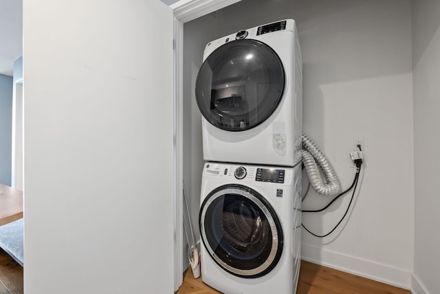 laundry room with stacked washer / dryer and wood-type flooring