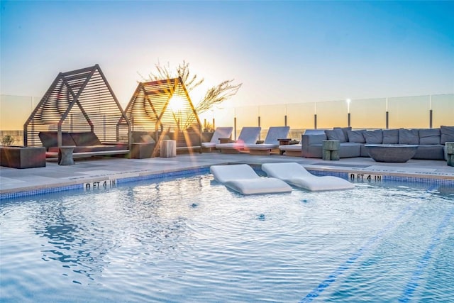 48 E Ave Unit 1607, Austin, TX 78701 - pool at dusk with an outdoor living space with a fireplace, a community pool, and a patio area