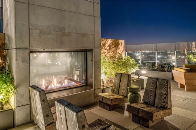 patio at night featuring a tile fireplace