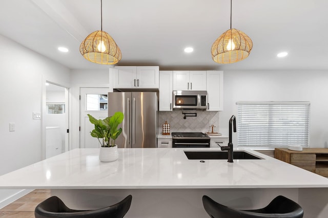 kitchen featuring stainless steel appliances, decorative light fixtures, light stone countertops, and white cabinets