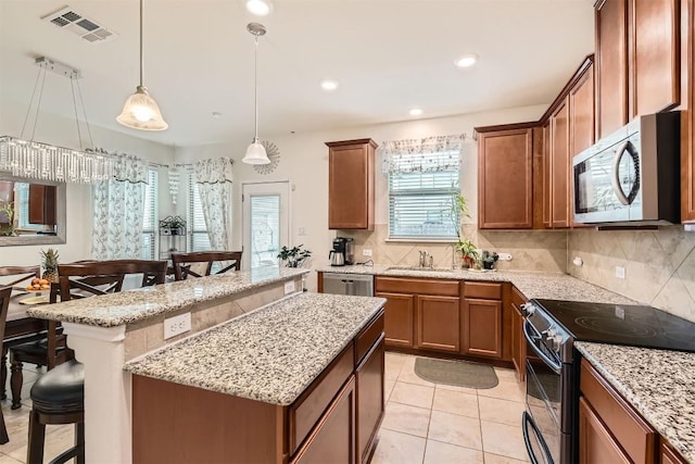 kitchen featuring decorative backsplash, light tile patterned floors, appliances with stainless steel finishes, decorative light fixtures, and a kitchen bar