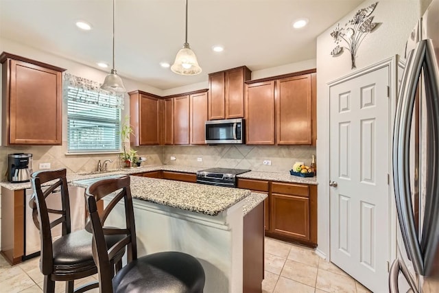 kitchen featuring a kitchen bar, light stone counters, pendant lighting, and stainless steel appliances