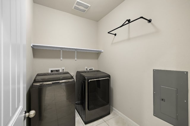 laundry area featuring washer and dryer, light tile patterned floors, and electric panel