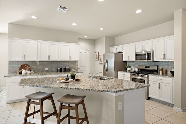 kitchen featuring white cabinets, stainless steel appliances, a kitchen island with sink, and sink