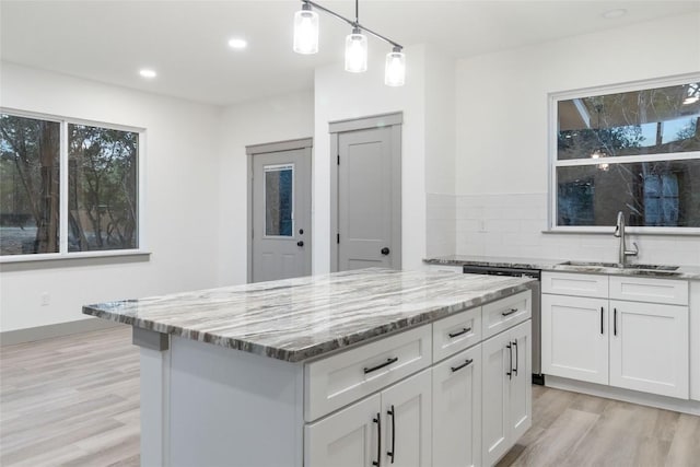 kitchen featuring tasteful backsplash, sink, light hardwood / wood-style flooring, white cabinets, and a kitchen island