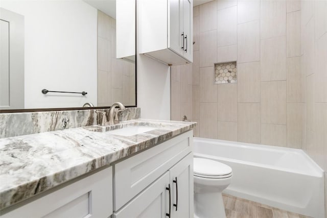 full bathroom with hardwood / wood-style floors, vanity, toilet, and tiled shower / bath combo