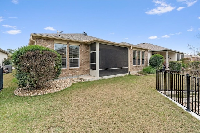 rear view of property featuring cooling unit, brick siding, fence, a sunroom, and a lawn