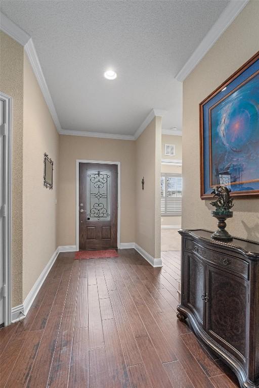 entryway featuring a textured ceiling, dark hardwood / wood-style floors, and ornamental molding