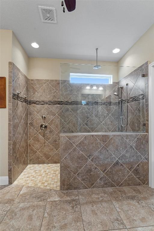 bathroom featuring a ceiling fan, visible vents, and walk in shower