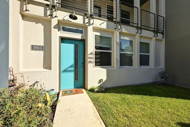 entrance to property featuring a yard and a balcony