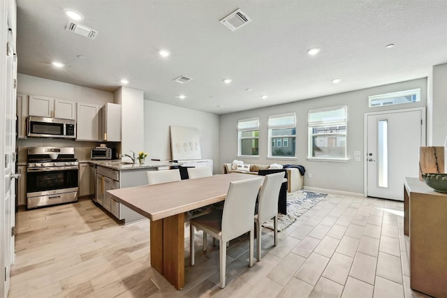 kitchen featuring light stone countertops, stainless steel appliances, tasteful backsplash, kitchen peninsula, and white cabinets