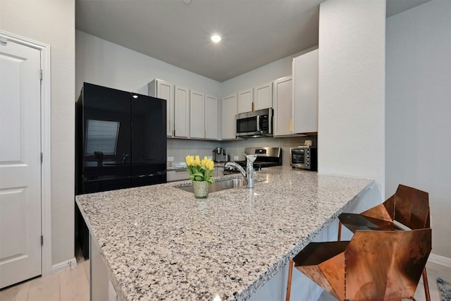 kitchen with white cabinetry, kitchen peninsula, stainless steel appliances, and a breakfast bar area