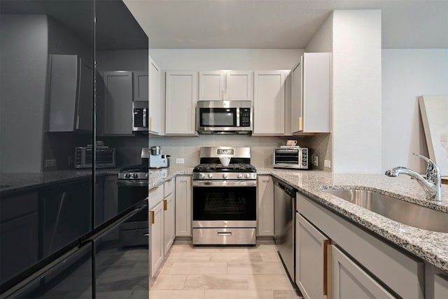 kitchen with white cabinetry, sink, stainless steel appliances, tasteful backsplash, and light stone counters