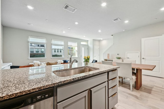 kitchen with dishwasher, light stone counters, sink, and light hardwood / wood-style flooring